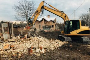 Excavator destroying brick house on land in countryside